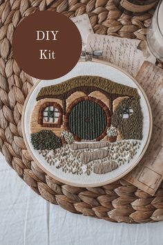 an embroidery pattern with a house and trees in the background on a woven place mat