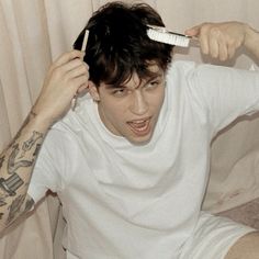 a man brushing his hair with a toothbrush in front of him, while sitting on the floor