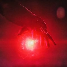 two hands reaching towards a glowing object in the dark night, with red light coming from it