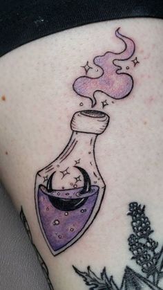 a woman's thigh with a tattoo on it that has an image of a flask and stars coming out of it