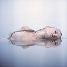 a woman is floating in the water with her eyes closed