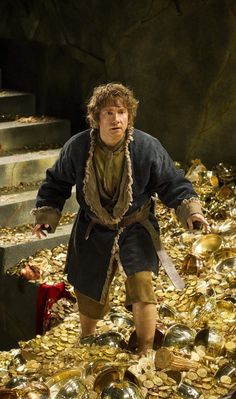 a man standing in front of a pile of gold coins