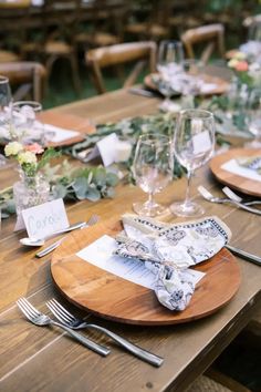 a wooden table topped with plates and glasses