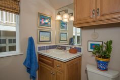 a bathroom with wooden cabinets and blue towels on the counter top, along with a potted plant