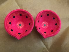 two pink paper bowls sitting on top of a piece of brown paper with black dots