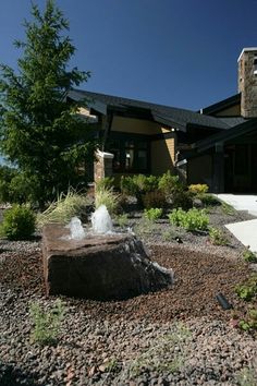 a large rock sitting on top of a gravel covered field next to a tall building