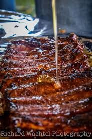 a person cutting into a piece of meat on top of a pan covered in sauce