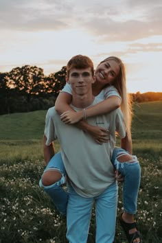 a man carrying a woman on his back in the middle of a field at sunset