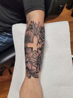 a person with a cross and flowers on their arm