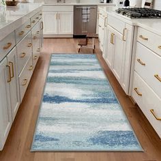 a kitchen with white cabinets and blue rugs on the wooden floor next to an oven