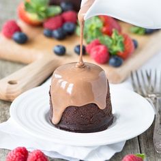 a chocolate cake is being drizzled with icing and topped with fresh berries