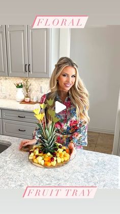 a woman standing in front of a bowl of fruit on top of a kitchen counter