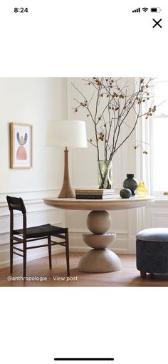 a vase with flowers on top of a table next to two chairs and a lamp