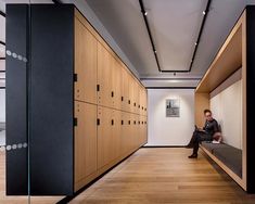 a man sitting on a bench in the middle of a room with many lockers