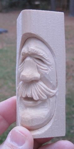 a hand is holding a carved white object in the shape of a man's face