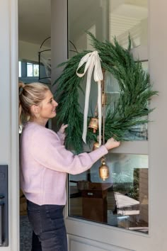 a woman is holding a wreath in front of the door