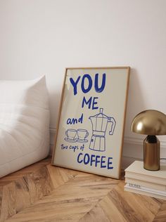 a sign that says you me and the cup is coffee next to a lamp on a wood floor