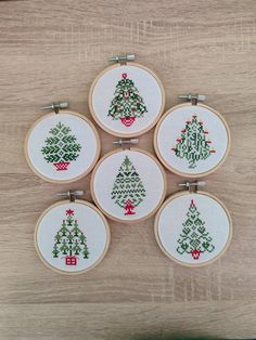 four cross stitch christmas trees are on the table