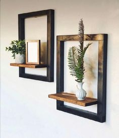 two wooden shelves with plants on them against a white wall, one holding a plant and the other displaying a framed photograph