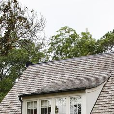 a white house with two windows and a roof that has shingles on the top