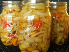 three jars filled with pickled vegetables sitting on a table