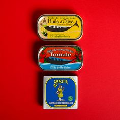 three tins of food sitting on top of a red surface