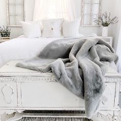 a white bed topped with pillows and blankets