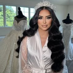 a woman wearing a tiara standing in front of wedding gowns