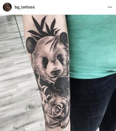 a panda bear tattoo on the right arm and shoulder, with roses around its neck