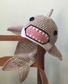 a crocheted shark hat on top of a wooden rocking chair with the mouth open