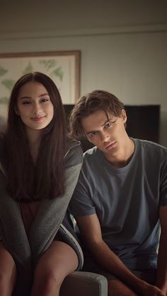 a young man and woman sitting on a couch