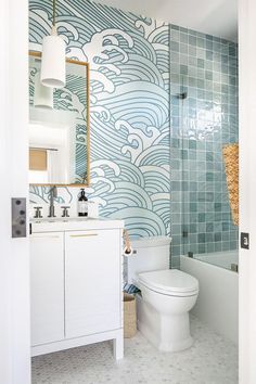 a white toilet sitting next to a bath tub in a bathroom under a mirror on top of a wall