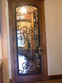 a wooden door with wrought iron designs on the glass and wood frame, in an entry way