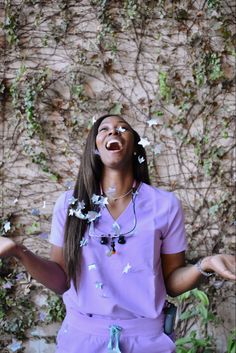 a woman standing in front of a wall with flowers on her head and hands out