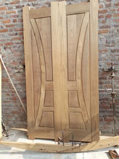 two wooden doors sitting next to each other in front of a brick wall and floor