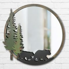 a mirror with a bear and trees in it on the wall next to a brick wall