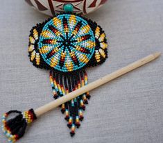 a beaded decoration next to a knitting needle