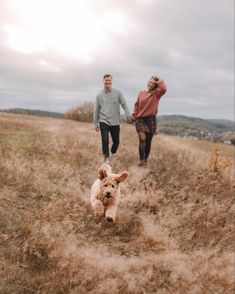 a man and woman walking down a hill with a dog