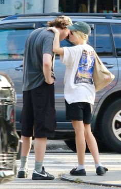 a young man and woman standing next to each other in front of a parking lot