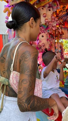 a woman with tattoos on her back standing in front of a carousel