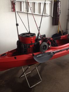 a red kayak in a garage with fishing rods and reels on the rack