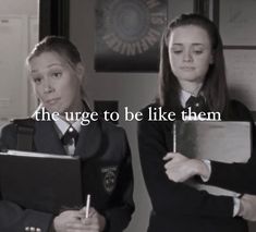 two girls dressed in school uniforms holding notebooks and writing on paper with the words, the urge to be like them