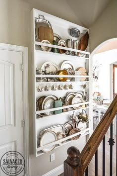 a white shelf filled with lots of dishes on top of a wooden bannister