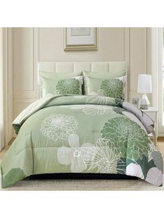 a green and white comforter set with flowers on the bed in front of a window