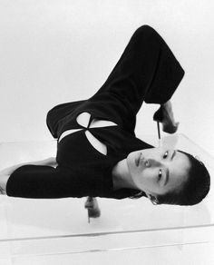 a man laying on top of a glass table next to a skateboard in the air