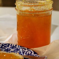 a jar of honey sitting on top of a table next to a plate with a piece of bread