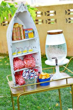 an old boat is turned into a shelf for drinks and snacks on a table in the yard