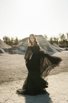 a woman in a long black dress is posing for the camera