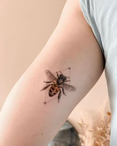 a small bee tattoo on the right upper arm