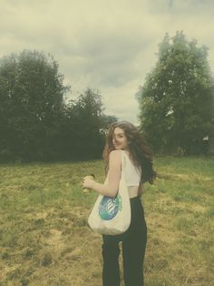 a woman carrying a bag in the middle of a field